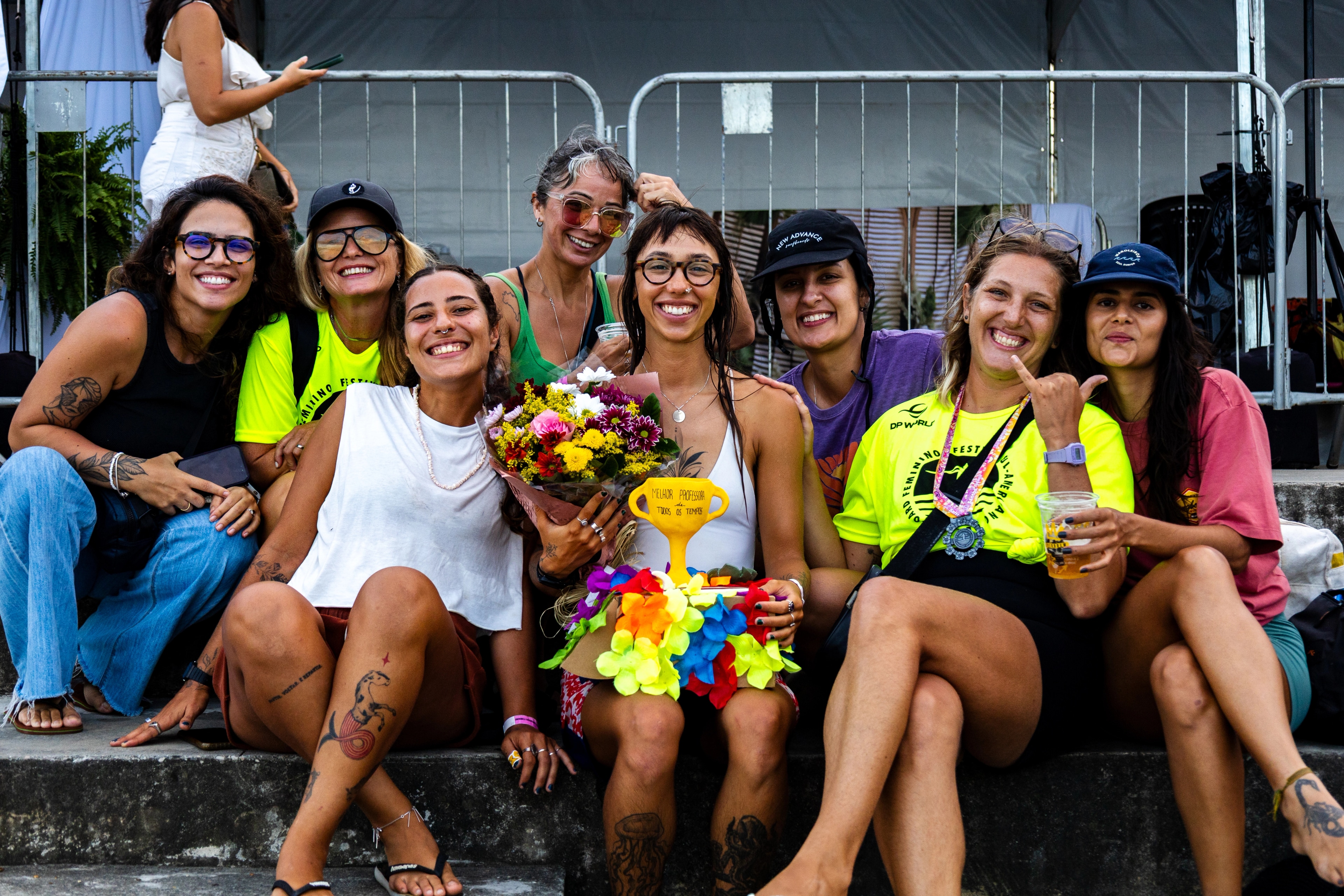 Grupo de amigas sorrindo com buquê e troféu no festival