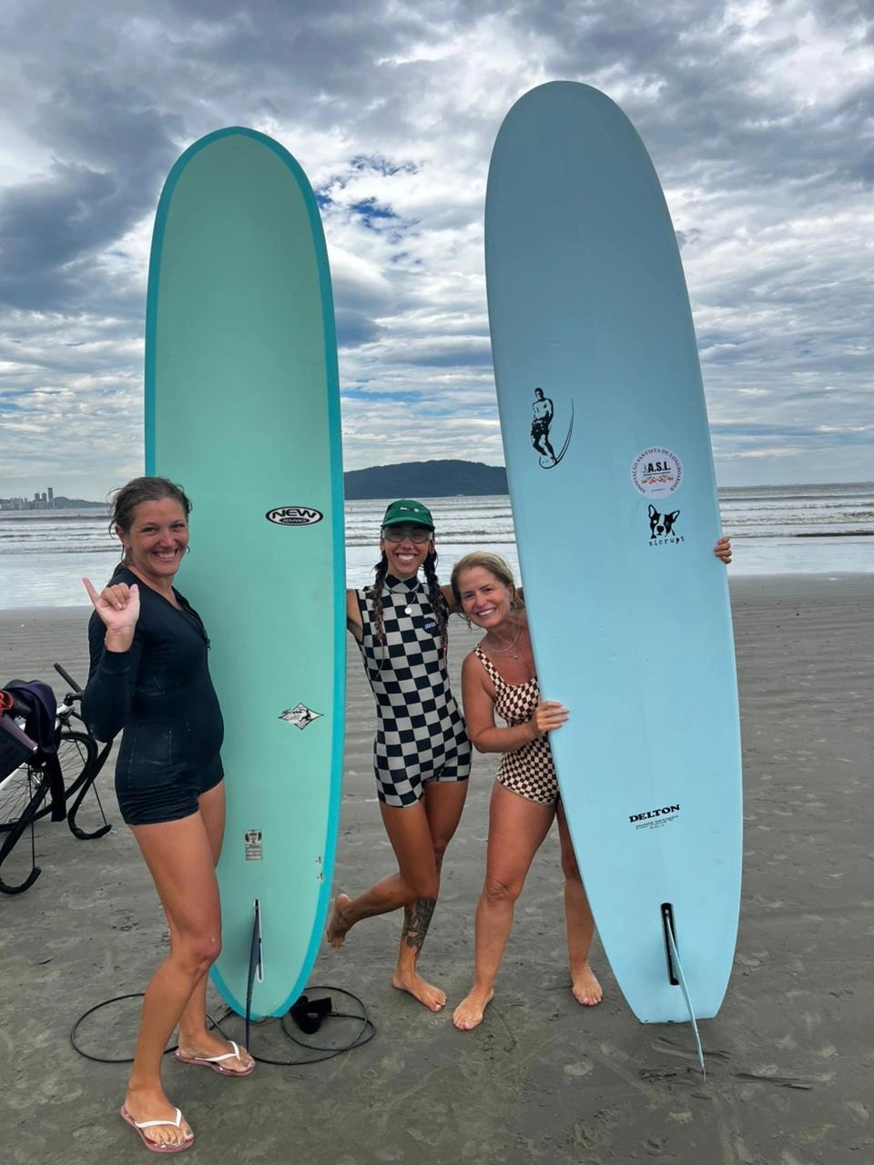 Três surfistas com pranchas longboard na praia